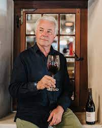 Winemaker holding a glass of red wine in front of a window