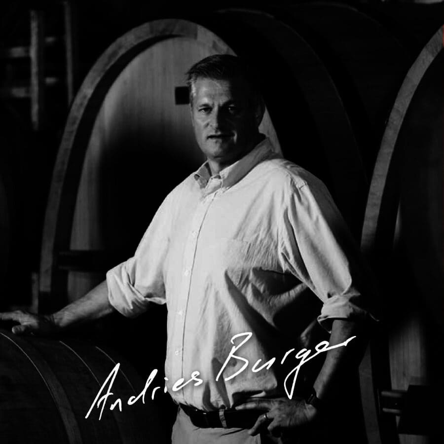 Andries Burger standing confidently among wine barrels at Simon Wine Emporium.