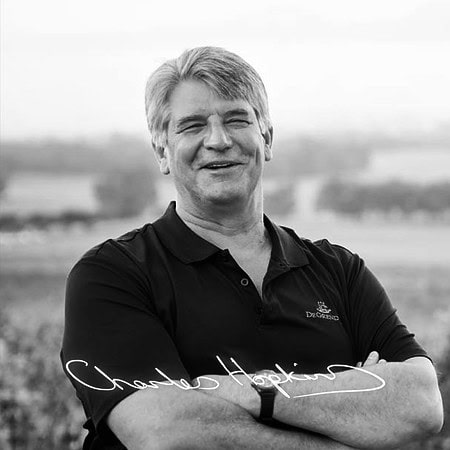 Smiling Winemaker In Stellenbosch Vineyard, Showcasing South African Wine Expertise.