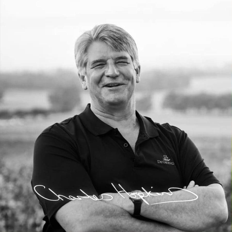 Smiling winemaker in Stellenbosch vineyard, showcasing South African wine expertise.