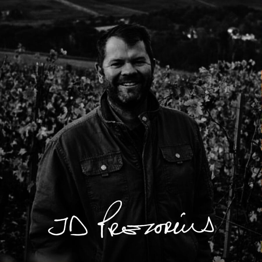 JD Prezorius smiling in a Stellenbosch vineyard, showcasing South African wine heritage.